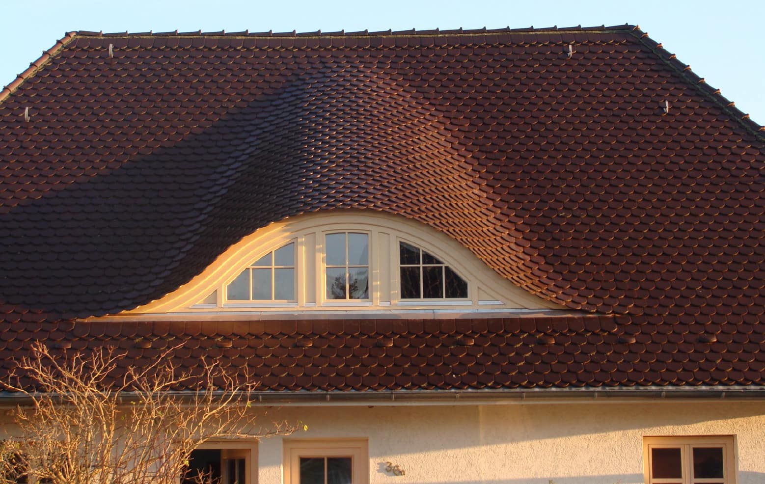 Wohnhaus mit roter Ziegeleindeckung und breiter Fledermausgaube