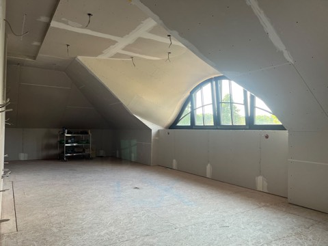 Fledermausgaube im Trockenbau: verkleidetes Dachgeschoss mit Rundbogenfenster